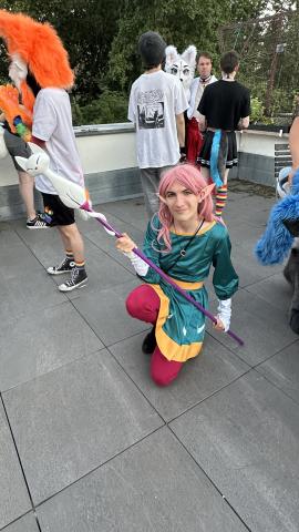 Cosplay von Amity-Blight in der Hecate-Version. Es ist ein Blaues Kleid mit mehreren Sichelmoden am Rockzipfel, ein goldener Gürtel sowie weiße Armstulpen.