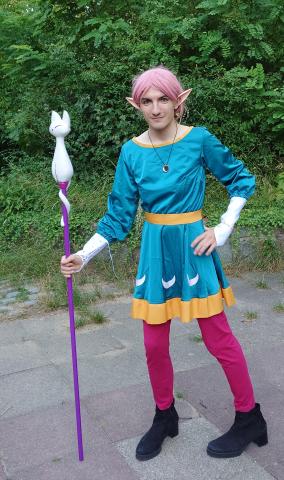 Cosplay von Amity-Blight in der Hecate-Version. Es ist ein Blaues Kleid mit mehreren Sichelmoden am Rockzipfel, ein goldener Gürtel sowie weiße Armstulpen.